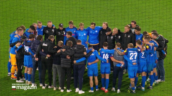 Fußballer und Trainer von Holstein Kiel bei der Mannschaftsbesprechung. © Screenshot 