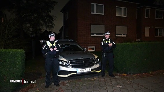 Zwei Polizistinnen stehen bei Nacht links und rechts neben einer Ausfahrt in der ein Polizeiauto geparkt ist. © Screenshot 