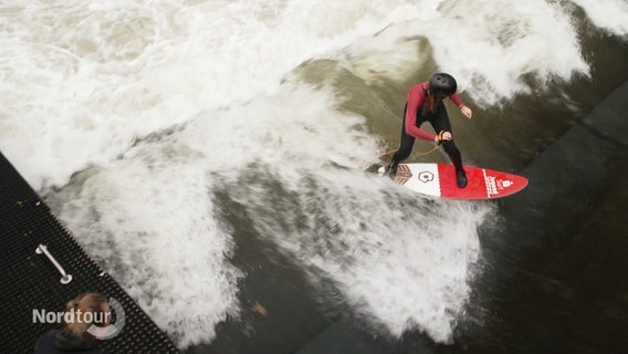 Eine Person surft auf einer stehenden Welle in einem Kanal. © Screenshot 