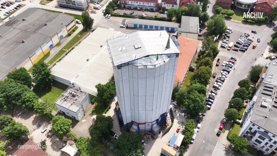 Blick aus der Vogelperspektive auf einen durch Baugerüste eingehüllten Wasserturm. © Screenshot 