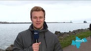 NDR-Reporter Dennis Mollenhauer steht am Rostocker Seekanal und berichtet. © Screenshot 