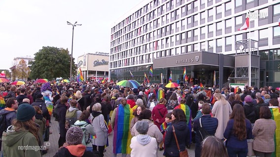 Menschen mit Regenbogenflaggen demonstrieren vor dem Neubrandenbruger Rathaus. © Screenshot 