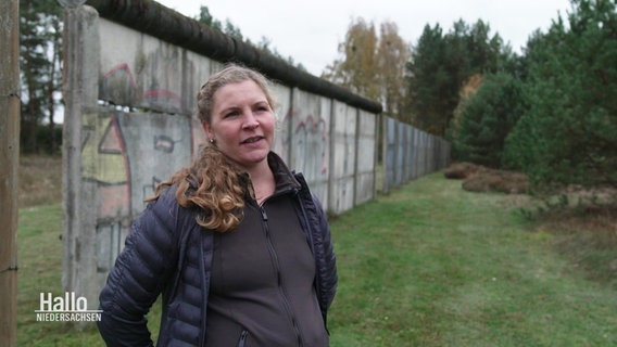 Anwohnerin Agnes Janke steht vor einem Überrest der Grenzmauer. © Screenshot 