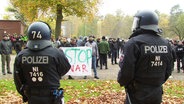 Polizisten sind von Hinten bei einer Art Demonstration zu sehen. © Screenshot 