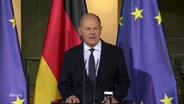 Bundeskanzler Olaf Scholz (SPD) am Rednerpult, im Hintergrund die Nationalflagge und die Europaflagge. © Screenshot 