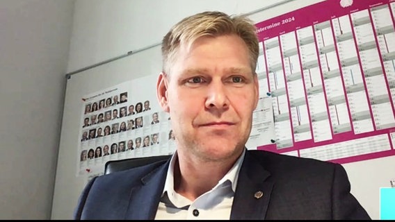 Screenshot von einem Interview: Der FDP-Bundestagsabgeordnete Christian Bartelt sitzt vor einer Wand, ab der ein Kalender hängt. © Screenshot 