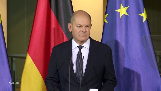 Bundeskanzler Olaf Scholz bei einer Rede. Er wirkt müde und hat harte Gesichtszüge. © Screenshot 