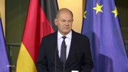 Bundeskanzler Olaf Scholz bei einer Rede. Er wirkt müde und hat harte Gesichtszüge. © Screenshot 