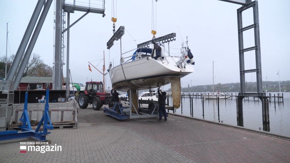 Ein Kran hievt ein Segelboot auf einen Anhänger. © Screenshot 