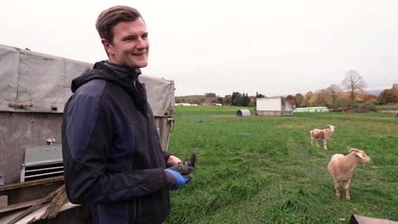 Ein Landwirt steht mit zwei Ziegen auf einer Wiese. © Screenshot 