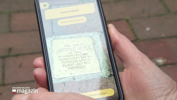 Eine Person scannt einen Stolperstein mit ihrem Handy. © Screenshot 