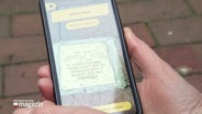 Eine Person scannt einen Stolperstein mit ihrem Handy. © Screenshot 