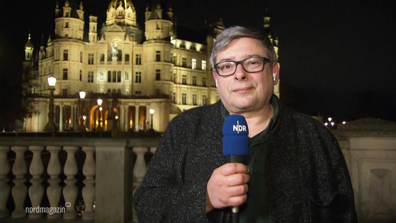 Reporter Frank Breuner steht mit einem Mikro vor dem Landtag in Schwerin. © Screenshot 