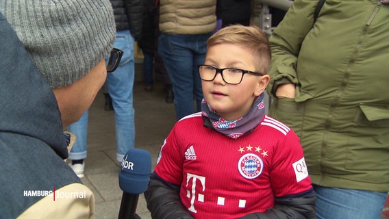 Ein junger Bayern-Fan wartet mit seinen Eltern vorm Hotel der Fußballer. © Screenshot 