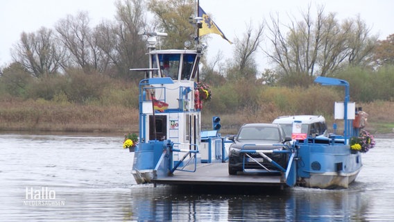 Eine kleine Fähre auf einem Fluss, darauf steht ein Auto. © Screenshot 