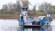 Eine kleine Fähre auf einem Fluss, darauf steht ein Auto. © Screenshot 