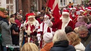 Viele Weihnachtsmänner laufen bei einem Umzug mit dänischer Fahne durch eine Menschenmenge. © Screenshot 