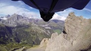 Jemand fliegt in einem Wingsuit durch ein Tal. © Screenshot 