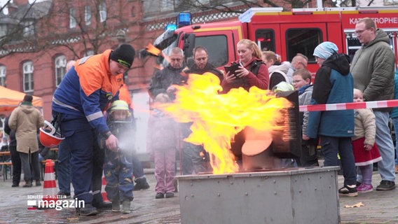 Bei einem Aktionstag stehen mehrere Menschen um ein Feuer herum © Screenshot 