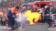 Bei einem Aktionstag stehen mehrere Menschen um ein Feuer herum © Screenshot 