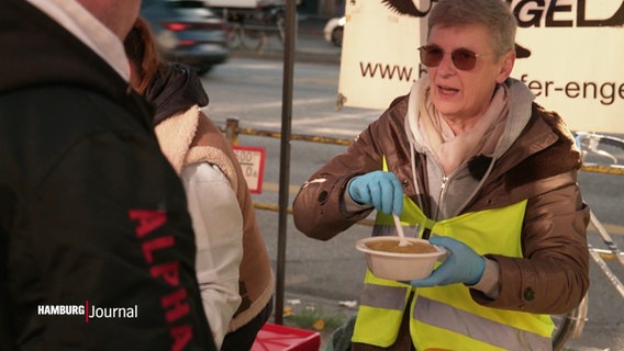 Gabi Liddell reiht einer Frau etwas zu essen. © Screenshot 