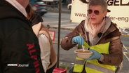 Gabi Liddell reiht einer Frau etwas zu essen. © Screenshot 