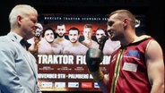 Boxer Denis Radovan mit Mikrofon, er spricht mit einem Mann mit weißem Sakko und Fliege, im Hintergrund ein Plakat der "Traktor Fight Night 1". © Screenshot 