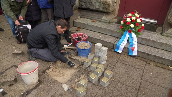 Ein Mann setzt Stolpersteine ein. © Screenshot 