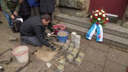 Ein Mann setzt Stolpersteine ein. © Screenshot 