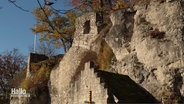 Blick auf eine in einen Felsen übergehende Burgruine © Screenshot 