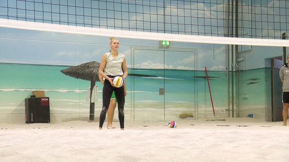 Eine Frau steht hinter einem Beachvolleyballnetz. © Screenshot 