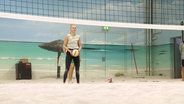 Eine Frau steht hinter einem Beachvolleyballnetz. © Screenshot 