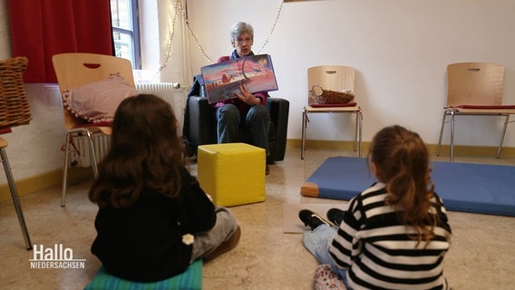 Astrid Grabenhorst Nitschke zeigt zwei Kindern ein Buch. © Screenshot 