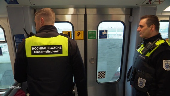 Zwei Hochbahnmitarbeiter stehen in der U-Bahn und schauen aus dem Fenster. © Screenshot 