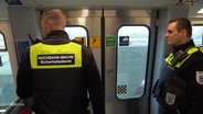 Zwei Hochbahnmitarbeiter stehen in der U-Bahn und schauen aus dem Fenster. © Screenshot 