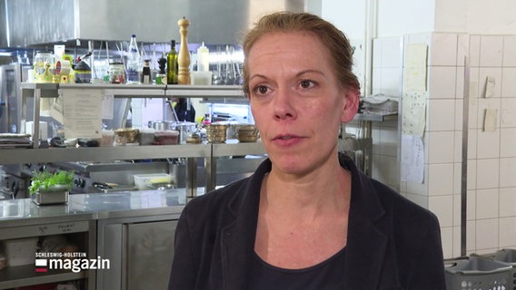 Hotelchefin Susen Erdmenger im Interview. Sie ist eine Frau mit hellen Haaren, die sie zum Zopf trägt und steht in einer Hotelküche. © Screenshot 