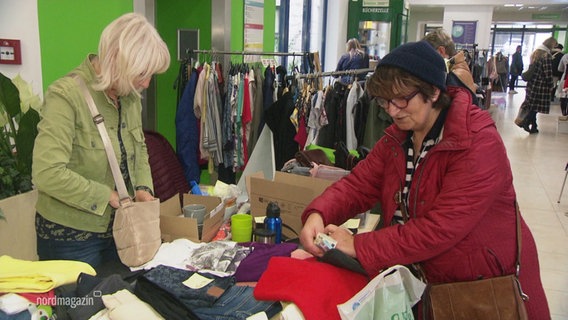 Auf einem Indoor-Flohmarkt schließen zwei Frauen an einem Stand einen Kauf ab. © Screenshot 