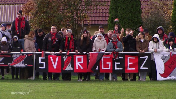 Fußballfans des SV Rogeez stehen am Spielfeldrand und jubeln © Screenshot 