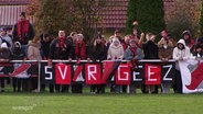 Fußballfans des SV Rogeez stehen am Spielfeldrand und jubeln © Screenshot 