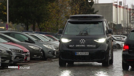 Ein fahrender, schwarzer Minibus von VW mit der Aufschrift "Self-driving-vehicle". © Screenshot 