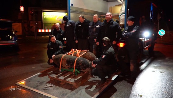 Das Team des Kampfmittelräumdienstes Niedersachsen bei einem Gruppenbild um zwei entschärfte Blindgänger aus dem Zweiten Weltkrieg. © Screenshot 