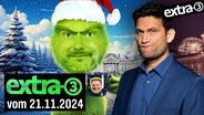 Christian Lindner als Grinch, der ein Glühweinbecher mit Christian Lindner drauf in der Hand hält. Daneben Christian Ehring. (extra 3 vom 21.11.2024 im Ersten) © NDR 