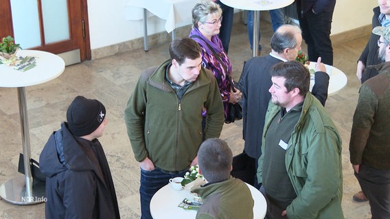 Landwirte stehen auf einer Konferenz um Stehtische herum und tauschen sich aus. © Screenshot 