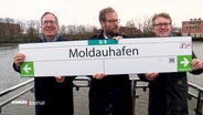 Drei Vertreter der Stadt halten ein Schild mit der Aufschrift "U4 Moldauhafen". © Screenshot 