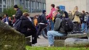 Schülerinnen und Schüler vor einer Schule. © Screenshot 