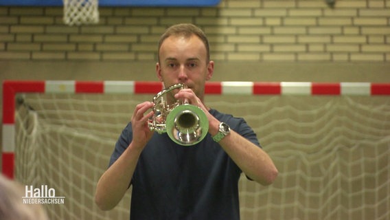 Ein Mann spielt in einer Turnhalle Trompete. © Screenshot 