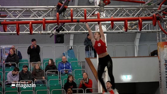 Eine Frau an einem Sportgerät eines Hindenislaufes © Screenshot 