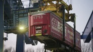 Am Port of Lübeck wird ein Container mit einem Kran transportiert. © Screenshot 