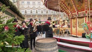 Musiker stehen neben einem Karussell auf dem Weihnachtsmarkt vor dem Hamburger Rathaus. © Screenshot 