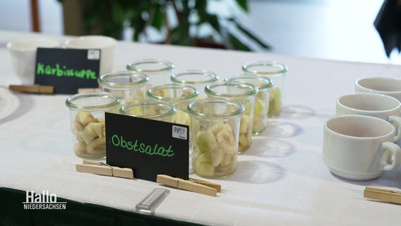 Kleine Gläschen mit geschnittener Banane, davor das Schild "Obstsalat". © Screenshot 